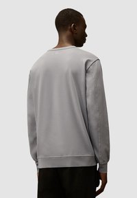 Grijze sweatshirt met een ronde hals, lange mouwen en een relaxte pasvorm. Zachte textuur met geribbelde manchetten en onderkant, minimale stikseldetails.