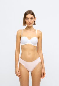 Soutien-gorge rembourré blanc avec bretelles ajustables et finition lisse, accompagné d'une culotte rose clair ornée de dentelle, vue de face sur un fond neutre.