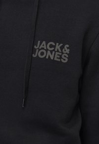 Sweat à capuche noir avec "JACK & JONES" imprimé en gris foncé sur la poitrine gauche et un cordon noir pendant à l’avant.