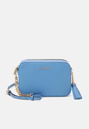 Vaaleansininen Michael Kors -laukku kullansävyisellä ketjulla, vetoketjulla ja sinisellä hapsukoristeella valkoisella taustalla.