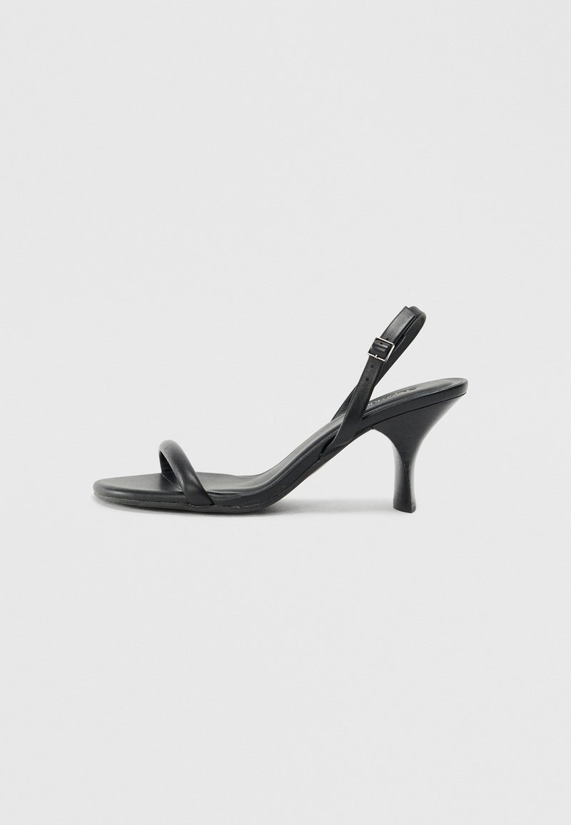 Black leather high-heeled sandals with a slim, curved heel and a crossed strap design. Adjustable ankle strap. Smooth texture.