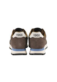 Brązowe zamszowe sneakersy z białymi ochraniaczami na pięty z wytłoczonym napisem "1968", niebieskimi akcentami i czarnymi gumowymi podeszwami; zaprojektowane dla komfortu i stylu.