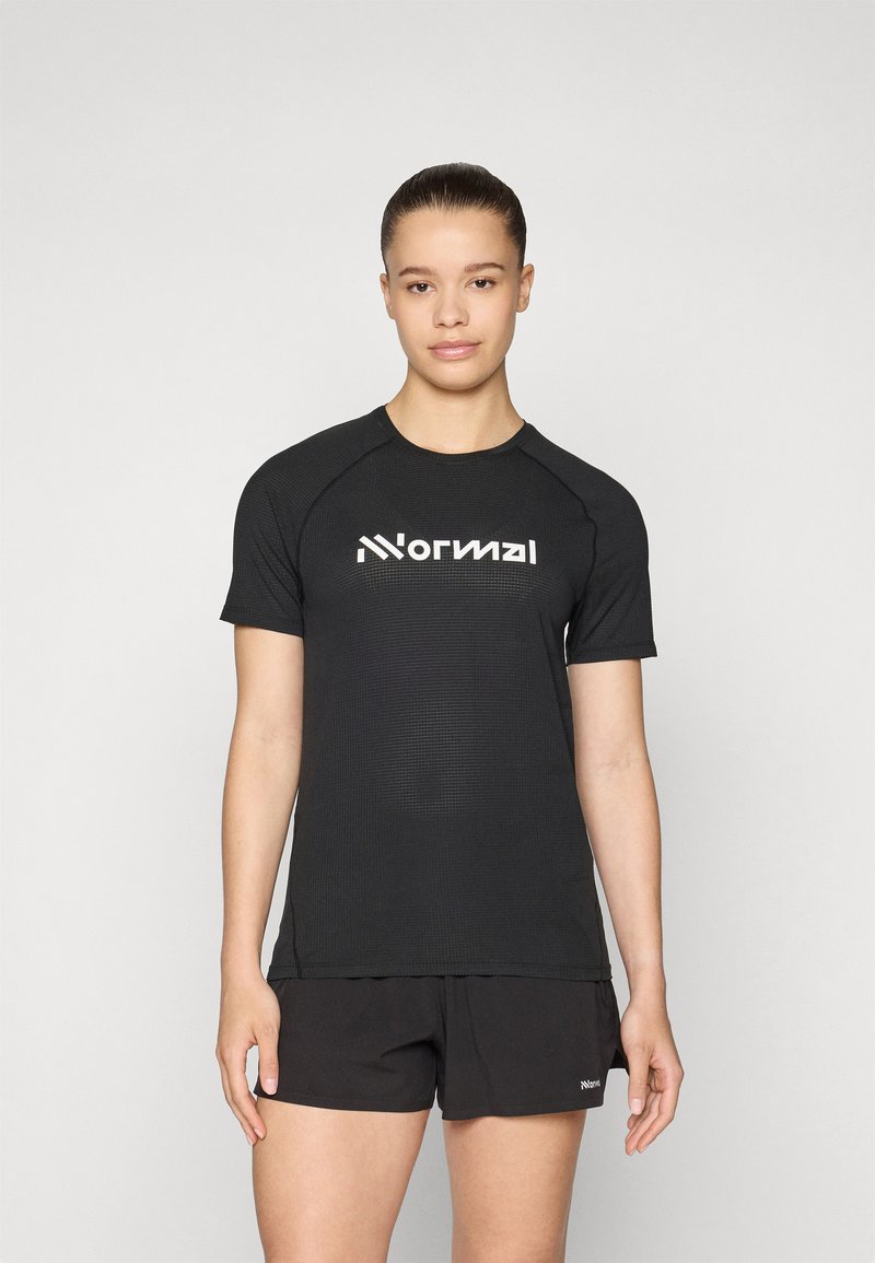 Svart trenings-T-skjorte med strukturert stoff, korte raglanermer, og en hvit logo sentrert på brystet. Kombinert med svarte shorts.