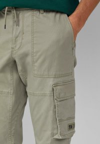 Lichtbeige cargobroek met een relaxed fit, voorzien van zijzakken, een trekkoord in de taille en subtiele stikseldetails.