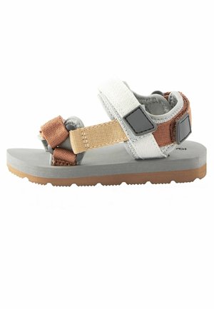 Sandale enfant à bout ouvert avec des brides en tissu réglables beige, blanc et marron, et une semelle grise rembourrée avec une semelle extérieure marron texturée.