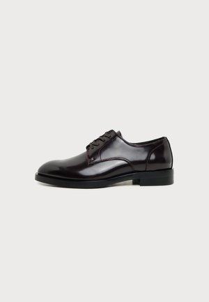 Shiny black leather men's dress shoe with lace-up front and low heel, shown in side profile on light background.