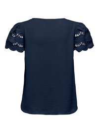 Blouse bleu marine en tissu texturé avec manches courtes bouffantes présentant des détails en dentelle découpée festonnée.