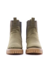 Botines de tobillo verde oliva con un upper de tela suave, paneles laterales elásticos y una suela de goma texturizada que presenta estrías horizontales.