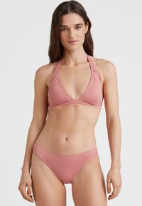 Rožinės bikini rinkinys, susidedantis iš halterio stiliaus viršaus su giliu V formos iškirpimu ir suderintų žemai nuleistų kelnaičių; lygi, elastinga medžiaga su minimaliais siūlais.