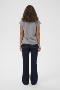 Grijze shirt met korte mouwen en een ontspannen pasvorm, gecombineerd met donkerblauwe flared jeans. Soepele stof met zichtbare stiksels en zakken.
