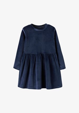 Donkerblauwe corduroy jurk met lange mouwen, ronde halslijn en geplooide rok. Verticale strepen voegen textuur aan de stof toe.