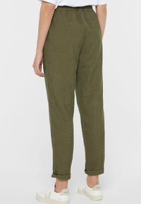 Olive green corduroy pants with a relaxed fit. Features an elastic waistband and rolled cuffs. Soft texture with vertical ribbing detail.
