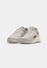Las zapatillas deportivas blancas cuentan con una parte superior de malla texturizada con acentos rojos y una suela acolchada. Diseño con cordones y con marca en la lengüeta.