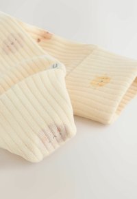 Ribētas gaiši dzeltenas zeķes ar rotaļīgiem dzīvnieku rakstiem aproču daļā, ar mīkstu tekstūru un vieglu elastību ērtībai.