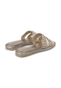 Metalen gouden slide-sandalen met gekruiste banden, versierd met heldere edelsteenversieringen, met een platte zool en rond teenontwerp.