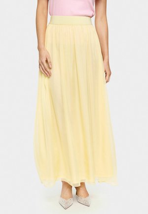 Yellow, knee-length skirt made of lightweight fabric with a flowing design and gathered waistband. Worn with silver-accented shoes.
