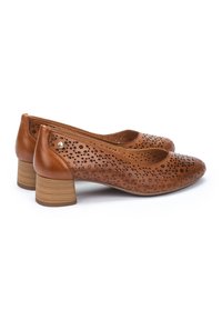 Chaussures en cuir perforé marron avec un bout arrondi et un petit talon en bois empilé. Présentent des motifs découpés en fleurs et un matériel minimal.
