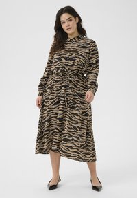 Lange mouw knoopsluiting jurk in tan en zwart zebra print, met een strikceintuur, vloeiende rok en een relaxte pasvorm. Semi-doorzichtige stof.