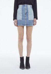 Denim mini hame, jossa on kaksivärinen muotoilu vaaleansinisten ja tummansinisten paneelien kanssa. Keskikorkea vyötärö ja suora leikkaus. Yhdistetty mustien nilkkabootsien kanssa.