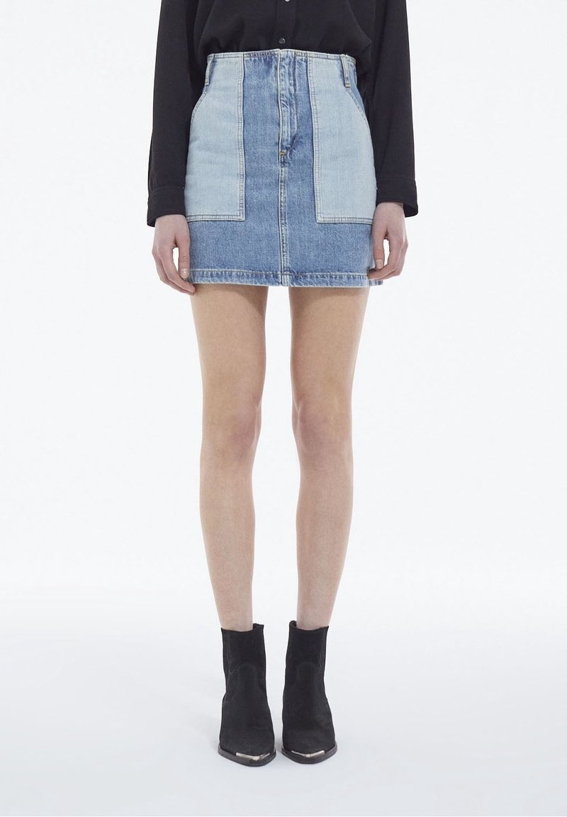 Denim mini hame, jossa on kaksivärinen muotoilu vaaleansinisten ja tummansinisten paneelien kanssa. Keskikorkea vyötärö ja suora leikkaus. Yhdistetty mustien nilkkabootsien kanssa.