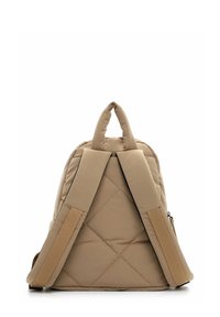 Bēša kviltēta mugursoma ar polsterētām regulējamām plecu siksnām un nelielu cilpu rokturi augšpusē, attēlota no aizmugures uz baltas virsmas.