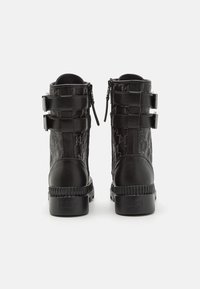 Stivaletti neri alla caviglia con tomaia in pelle testurizzata, caratterizzati da doppi cinturini con fibbia e punta tonda. Suole spesse in gomma con dettaglio logo impresso.