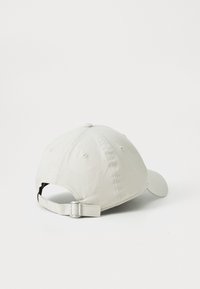 Cappello da baseball beige regolabile visto da dietro con chiusura a gancio in metallo su sfondo bianco.