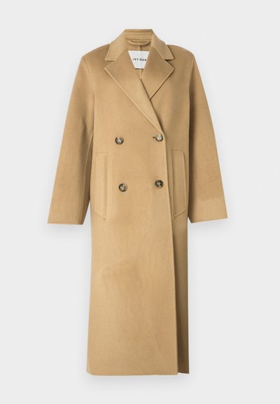 Cappotto in misto lana beige con design doppiopetto, caratterizzato da grandi bottoni, rever a punta e due tasche frontali.