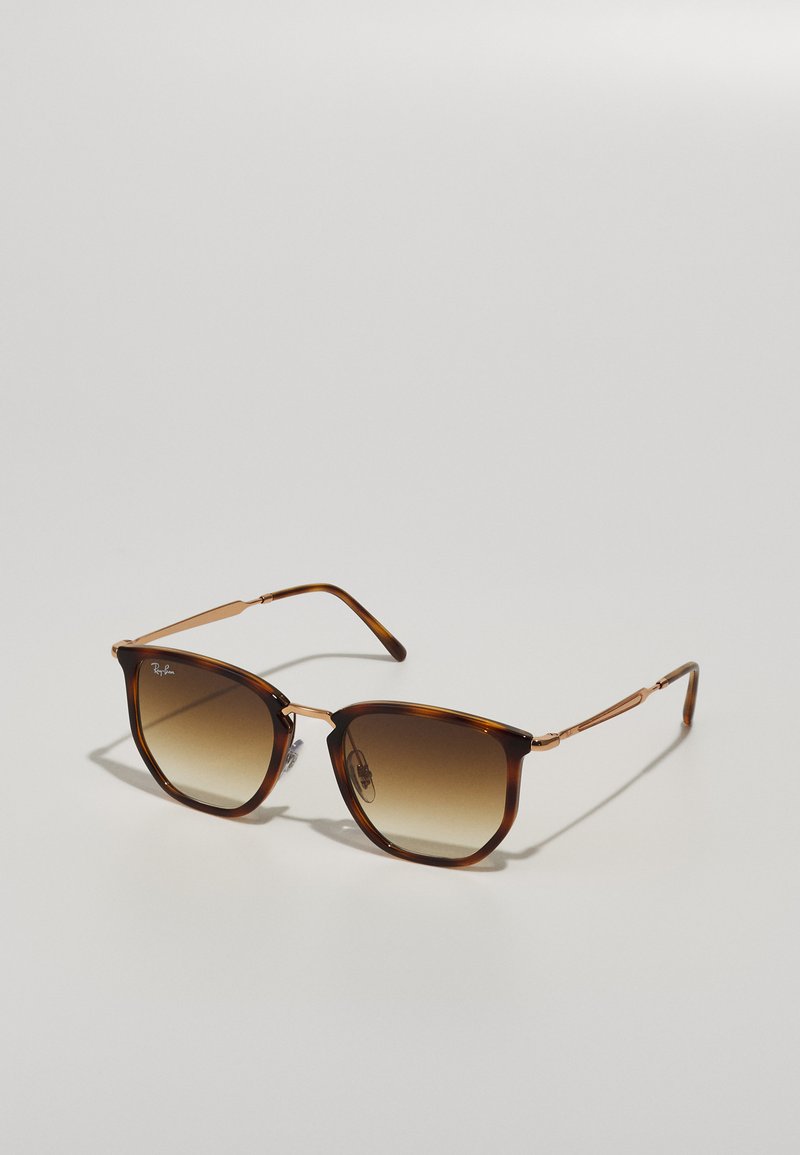Óculos de sol de tartaruga com lentes castanhas em degradê, detalhes em metal e design de armação angular. Apresenta hastes finas e flexíveis em metal.