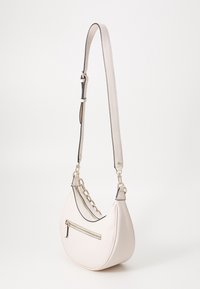 Crème lederen schoudertas met een gebogen vorm, een afneembare schouderband met kettingaccent, een buitenzak met rits en contrasterende randstiksels.