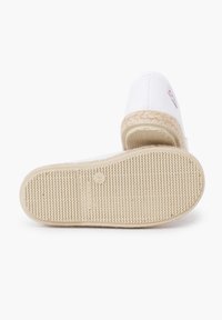 Espadrille en toile blanche avec une semelle en jute tissée et un fond en caoutchouc. Dotée d'un petit patch logo sur le côté. Design à bout arrondi et plat.