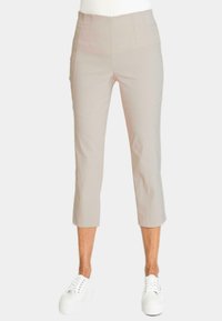 Beige cropped broek met een zachte textuur, met een hoge taille en gestikte zijzakken, gecombineerd met witte sneakers.