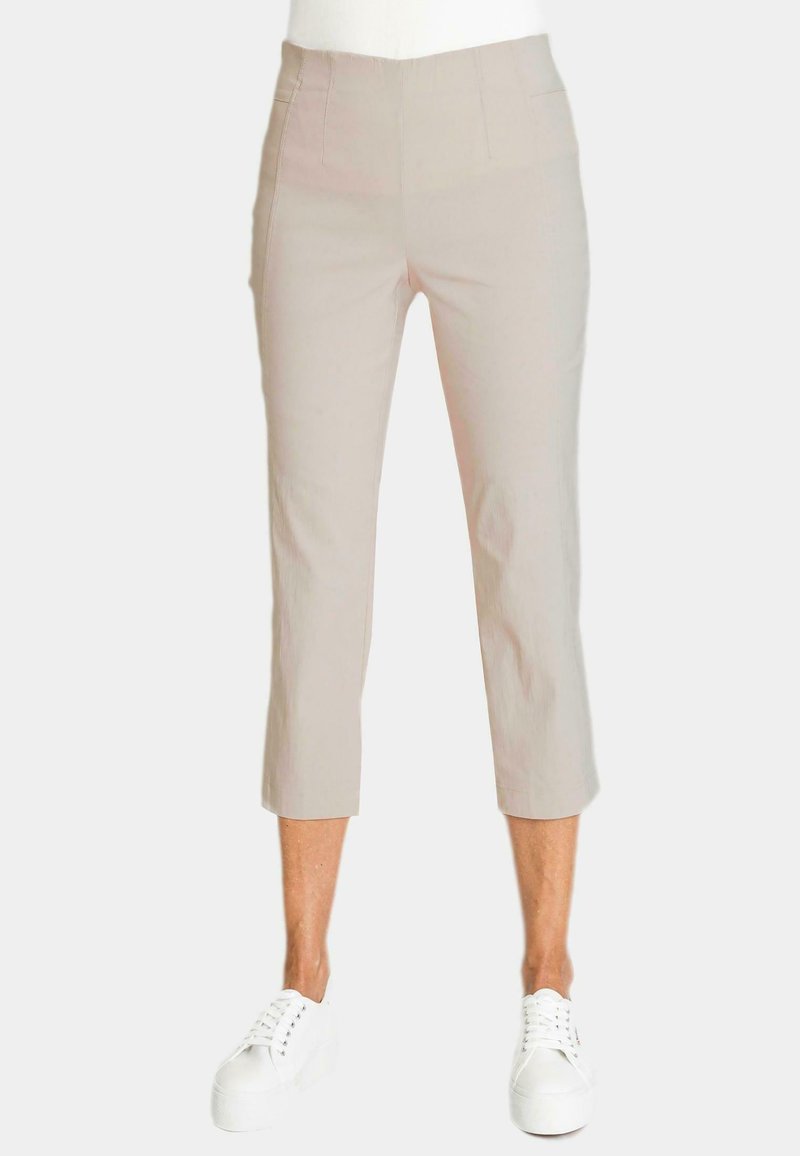 Beige cropped broek met een zachte textuur, met een hoge taille en gestikte zijzakken, gecombineerd met witte sneakers.