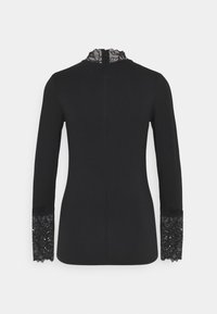 Zwarte blouse met lange mouwen en een textuur van kant bij de kraag en de manchetten, met een getailleerde silhoët en een naad aan de achterkant.