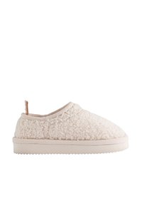 Chausson doux couleur crème avec dessus en tissu texturé, semelle rembourrée et petite languette arrière, présenté en profil latéral sur fond blanc.