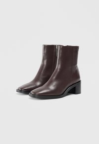 Dark brown leather ankle boots with side zipper and low block heel on a white background.