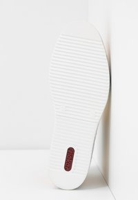 Biała gumowa podeszwa buta z poziomymi rowkami, z czerwonym logo "rieker" na środku i zaokrąglonym kształtem palców.