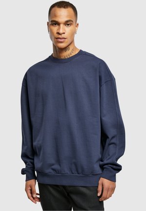 Sweatshirt bleu marine en tissu doux, avec une coupe décontractée, des poignets côtelés et un col rond. Design simple et sans couture.