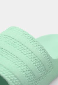 Mint green slide sandal with textured stripes, featuring a soft material and open design, ideal for casual wear and easy to clean.
