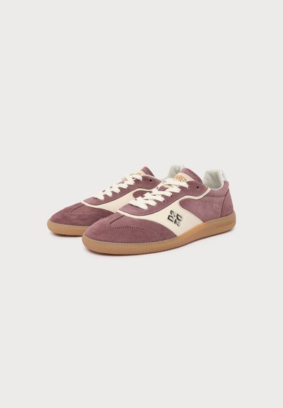 Paire de baskets basses en daim mauve discret et crème avec lacets blancs et semelles en gomme sur fond blanc.