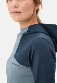Felpa con cappuccio a maniche lunghe di colore blu navy e grigio chiaro, realizzata in tessuto liscio con un design aderente. Presenta il logo sul petto e sulla manica.