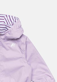 Giacca impermeabile di un leggero viola con cappuccio regolabile, caratterizzata da una fodera interna a righe e un logo bianco sul petto.