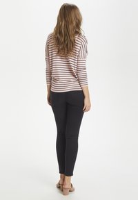 Ljust rosa randig tröja med trekvartslånga ärmar, ihop med svarta skinny jeans och beiga klacksandaler med blockklack. Bakifrån.