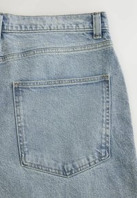 Tissu en denim bleu clair avec une grande poche carrée à l'arrière et une passants de ceinture à la taille.