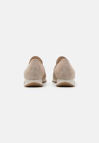 Scarpe slip-on in suede beige con punta rotonda e tacco basso, caratterizzate da un design posteriore liscio e una suola bianca a contrasto.