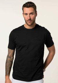 Černé tričko s krátkým rukávem vyrobené z bavlny s kulatým výstřihem, které má tónový logo potisk na hrudi a hladkou texturu.