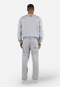 Gray sweatshirt and sweatpants set made from cotton blend. Features ribbed cuffs, relaxed fit, and a logo patch on the back.