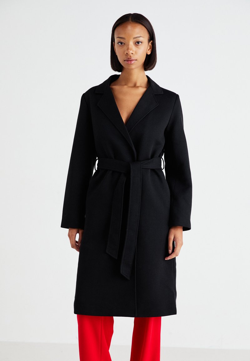 Black, long-sleeved coat with a lapel collar and tied belt at the waist. Made from a textured fabric with a straight cut.