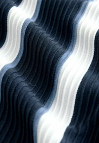 Tela elástica con ondas alternas en azul marino, azul claro y blanco. La textura es acanalada, creando profundidad visual y suavidad.