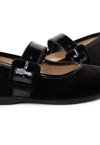 Zapatos Mary Jane de ante negro con una correa de charol brillante, detalle de hebilla cuadrada y un tacón bajo. El forro interior suave completa el diseño.